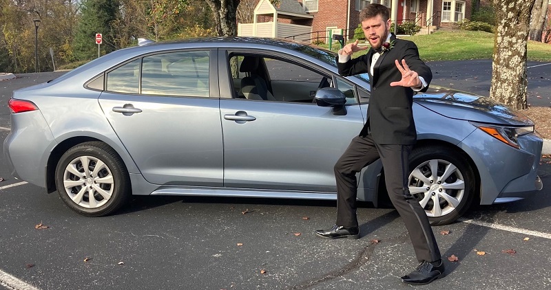 picture of Nathaniel Blalock wearing a Tuxedo in martial arts pose standing in front of a car