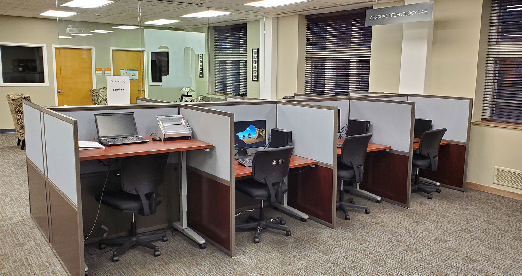 Four stations in the assistive technology lab equipped with computers and adjustable desks